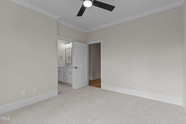 unfurnished bedroom featuring ensuite bathroom, ceiling fan, crown molding, and light colored carpet