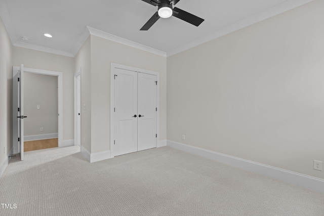 unfurnished bedroom with ornamental molding, a closet, light colored carpet, and ceiling fan