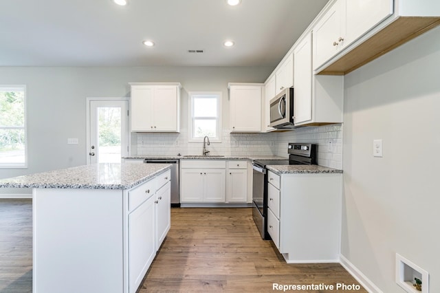 kitchen featuring white cabinets, backsplash, appliances with stainless steel finishes, and a center island