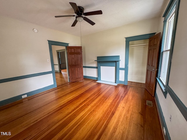 unfurnished bedroom with a closet, hardwood / wood-style floors, ceiling fan, and a textured ceiling