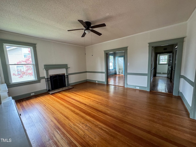 unfurnished living room featuring crown molding, hardwood / wood-style floors, ceiling fan, and a textured ceiling