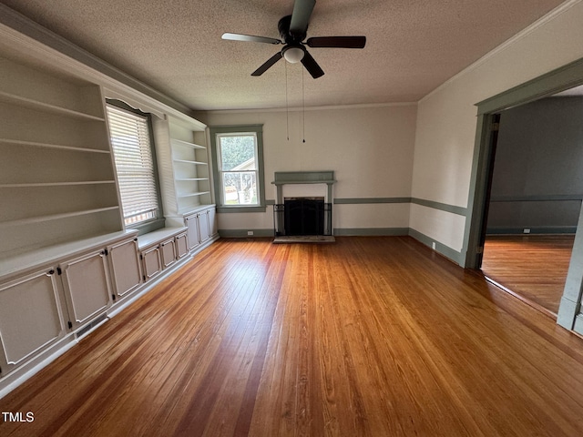 unfurnished living room featuring a textured ceiling, ceiling fan, crown molding, light hardwood / wood-style flooring, and built in features