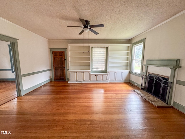 unfurnished living room with light wood-type flooring, a textured ceiling, ceiling fan, and ornamental molding