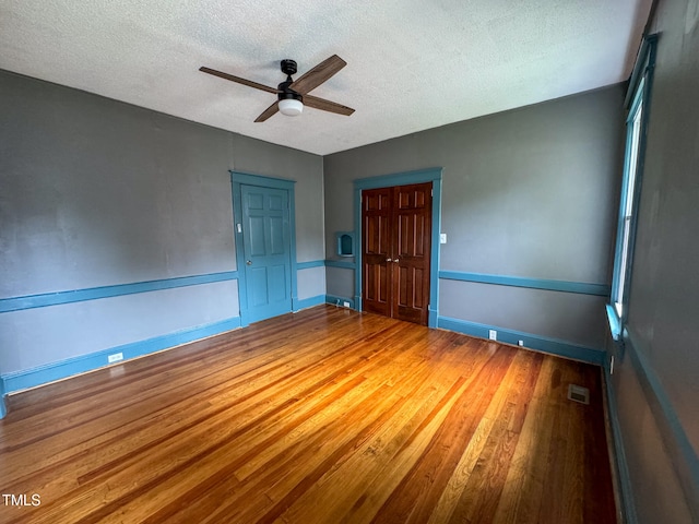 spare room with hardwood / wood-style floors, a textured ceiling, and ceiling fan