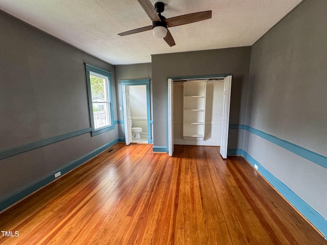 unfurnished bedroom with hardwood / wood-style floors, ceiling fan, a textured ceiling, and a closet