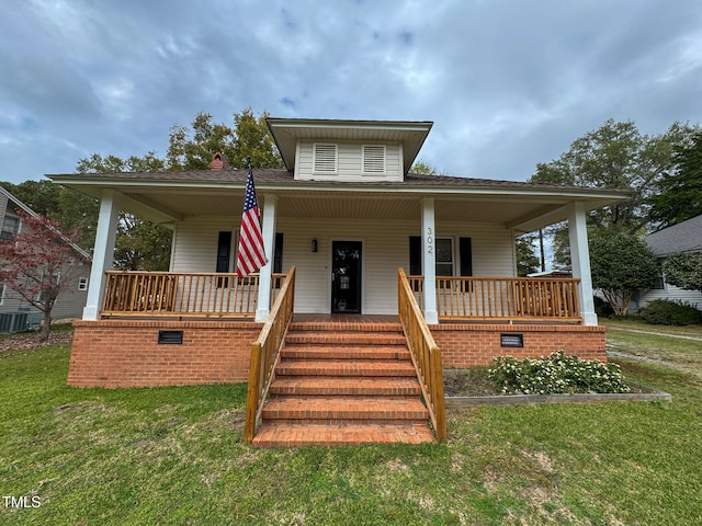 view of front of property featuring central air condition unit, a front yard, and covered porch