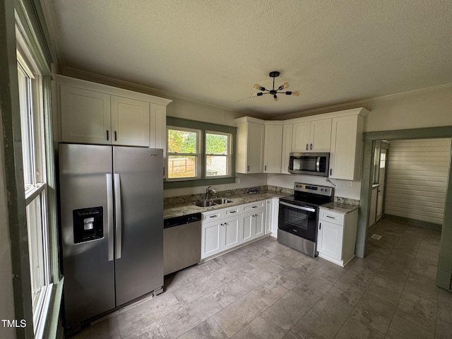 kitchen with stone counters, white cabinets, a textured ceiling, and stainless steel appliances