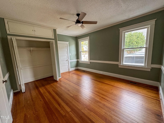 unfurnished bedroom with ceiling fan, multiple windows, a textured ceiling, and wood-type flooring