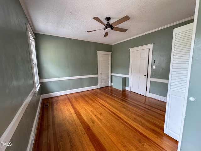 unfurnished bedroom featuring ceiling fan, wood-type flooring, a textured ceiling, and crown molding