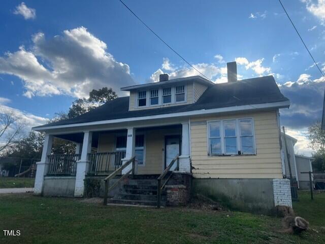 bungalow-style home featuring a front lawn and covered porch