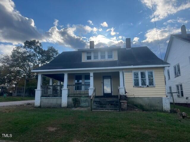 bungalow featuring covered porch and a front yard