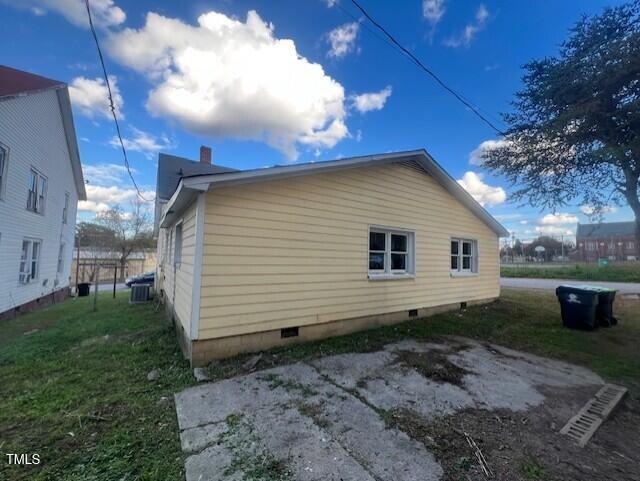 view of side of home featuring cooling unit and a lawn