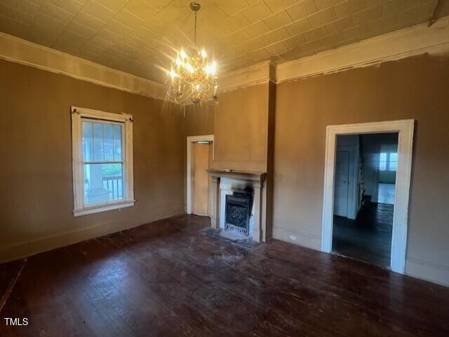 unfurnished living room featuring an inviting chandelier, hardwood / wood-style floors, and ornamental molding