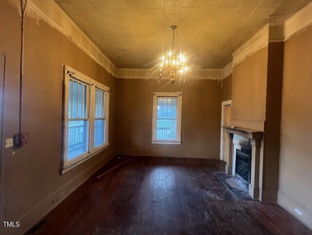 unfurnished living room featuring an inviting chandelier, dark hardwood / wood-style floors, and crown molding