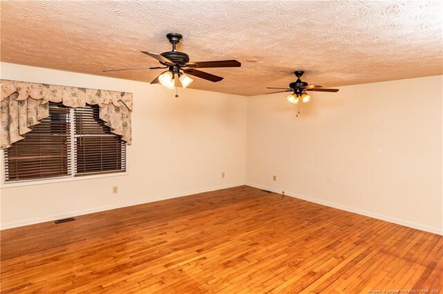 unfurnished room with ceiling fan, wood-type flooring, and a textured ceiling