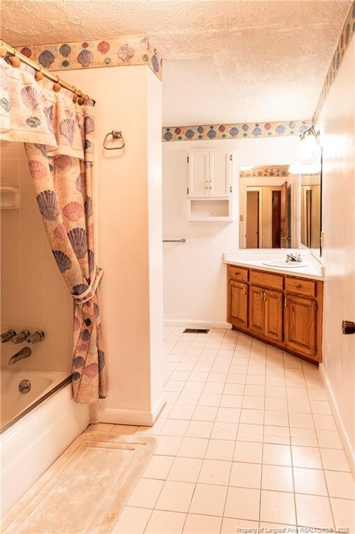 bathroom with vanity, tile patterned floors, shower / bath combination with curtain, and a textured ceiling