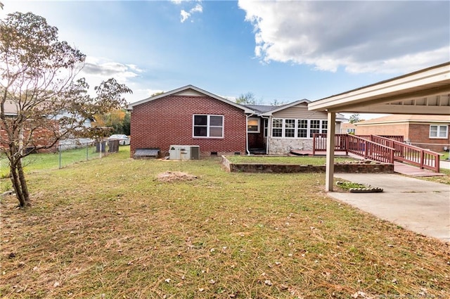 rear view of property with a wooden deck, cooling unit, and a yard