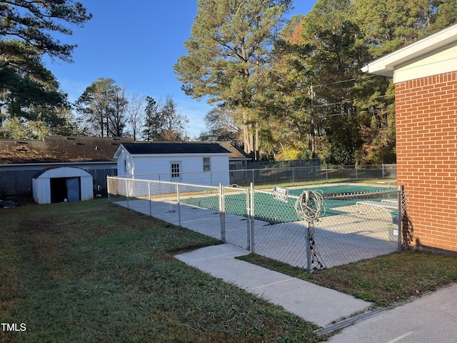 view of pool featuring an outbuilding, a fenced in pool, fence, a patio area, and a lawn