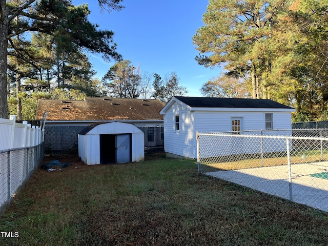 rear view of house with an outbuilding, a lawn, a storage unit, and a fenced backyard