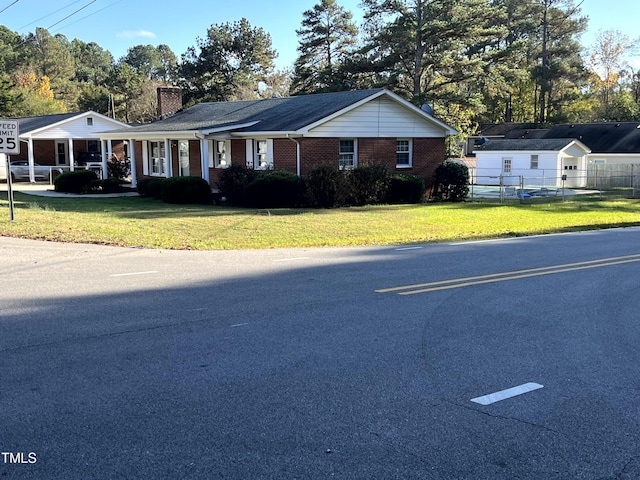 view of front of property featuring brick siding, a chimney, a front yard, and fence