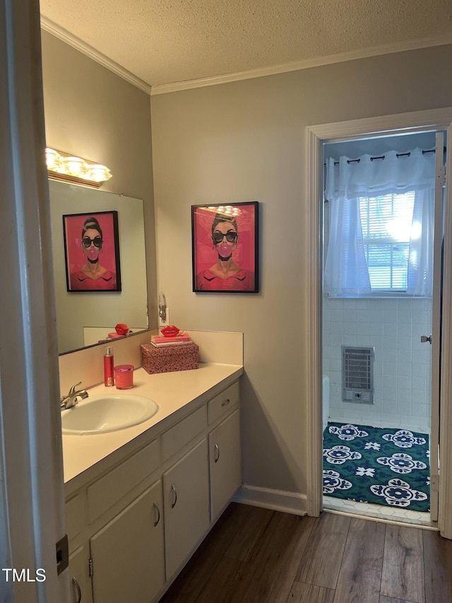 full bath with ornamental molding, wood finished floors, heating unit, a textured ceiling, and vanity