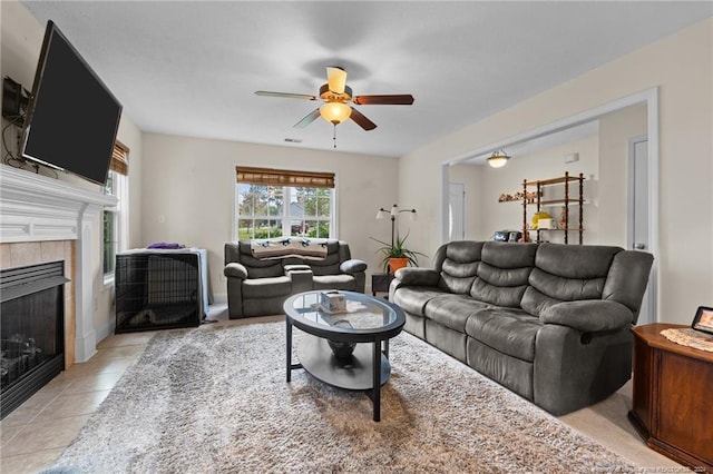 living room featuring a fireplace, ceiling fan, and light tile patterned floors