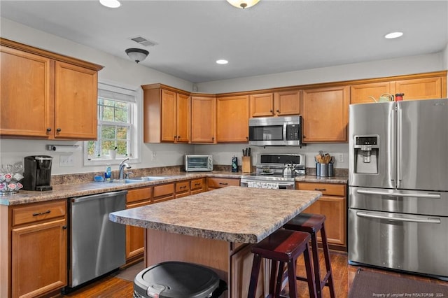 kitchen featuring stainless steel appliances, dark hardwood / wood-style flooring, sink, a breakfast bar area, and a center island