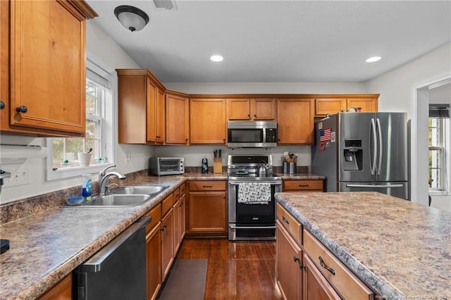 kitchen with appliances with stainless steel finishes, sink, and dark hardwood / wood-style floors