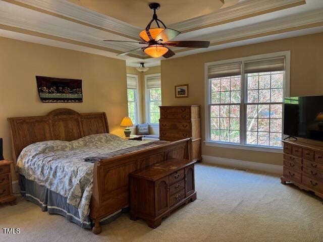 bedroom with a raised ceiling, light carpet, ceiling fan, and crown molding