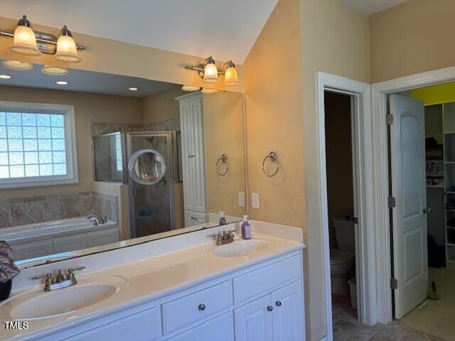 full bathroom featuring shower with separate bathtub, toilet, vanity, and vaulted ceiling