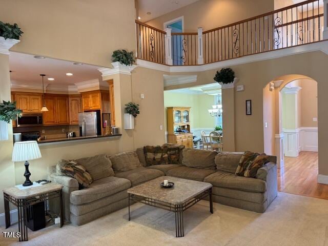 living room with ornamental molding, light hardwood / wood-style flooring, a chandelier, and a high ceiling