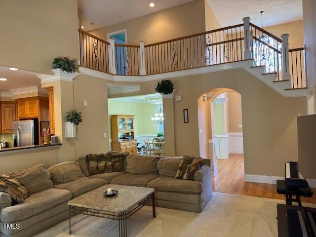 living room with a high ceiling, an inviting chandelier, light hardwood / wood-style floors, and plenty of natural light