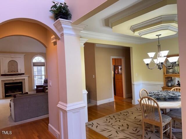 dining area with ornamental molding, light wood-type flooring, a chandelier, and ornate columns