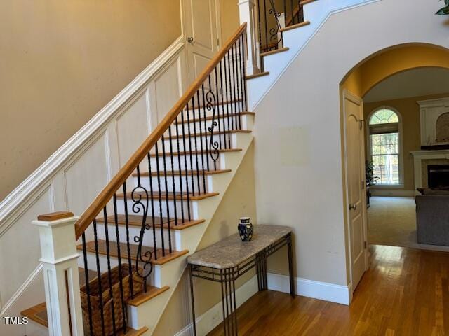 2012 Silverleaf Dr, Youngsville, NC 27596 - stairs featuring arched walkways, wood finished floors, a decorative wall, and a fireplace