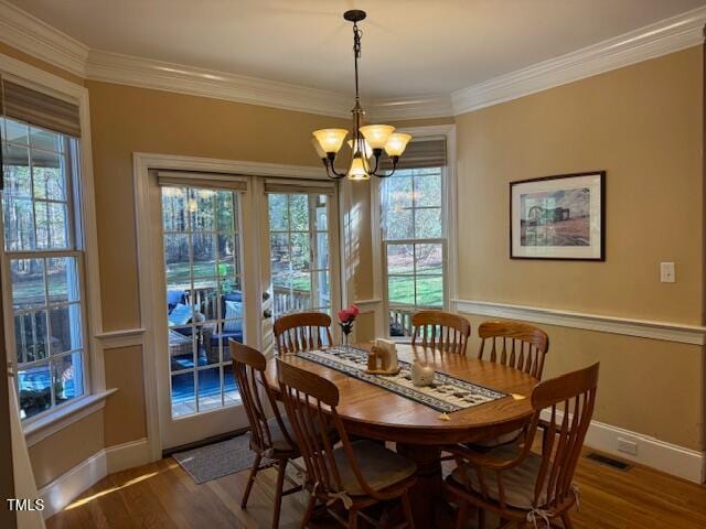 dining space with hardwood / wood-style flooring, a notable chandelier, and ornamental molding