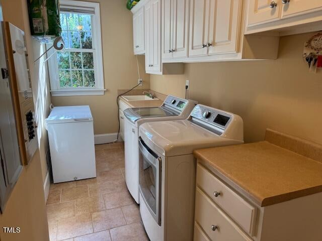 clothes washing area with washer and clothes dryer, cabinets, and sink