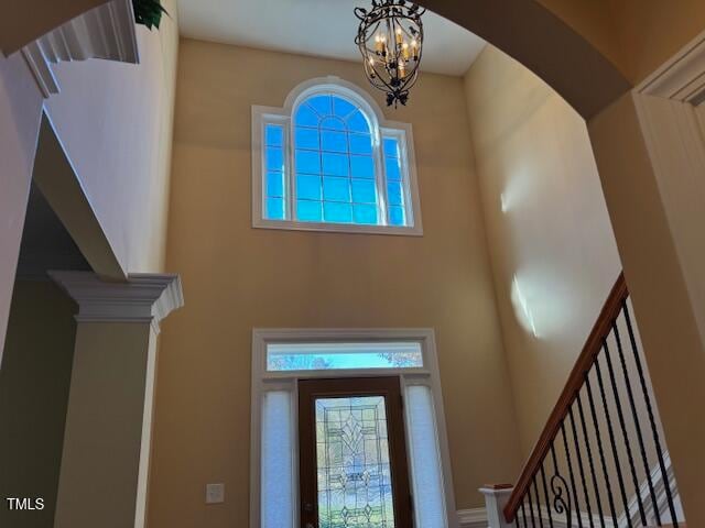 entrance foyer with a high ceiling, an inviting chandelier, and ornate columns