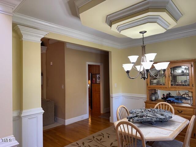 2012 Silverleaf Dr, Youngsville, NC 27596 - dining room featuring a chandelier, wood finished floors, crown molding, ornate columns, and wainscoting