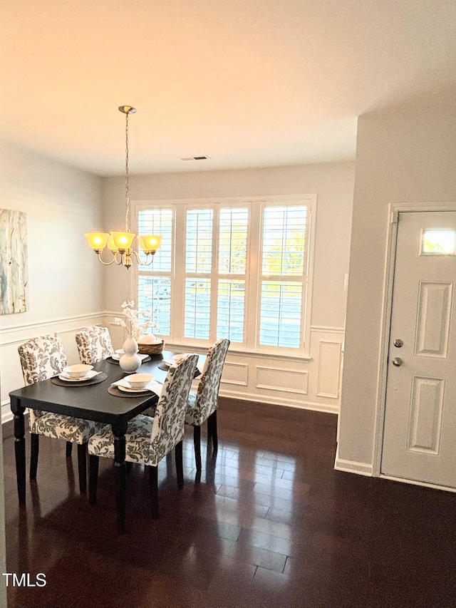 dining area with plenty of natural light, dark hardwood / wood-style floors, and an inviting chandelier