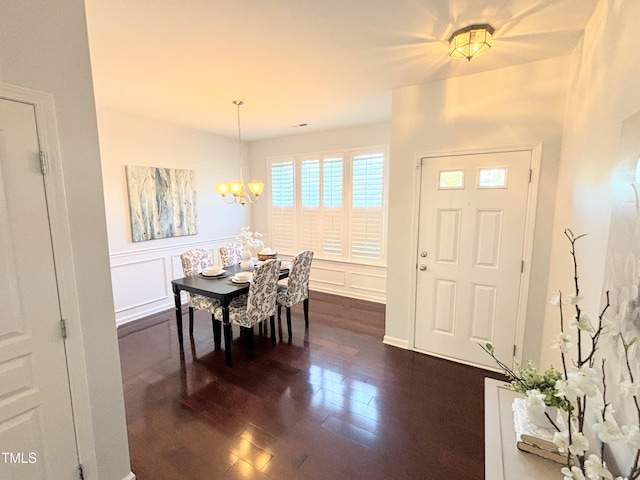 dining space with dark wood-type flooring and a notable chandelier