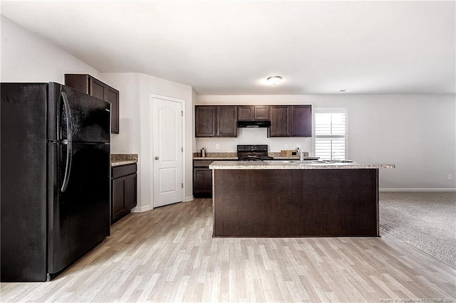 kitchen featuring dark brown cabinets, light hardwood / wood-style flooring, black appliances, and a center island with sink