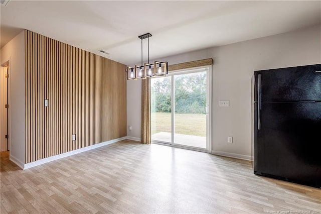 unfurnished dining area featuring wooden walls and light wood-type flooring