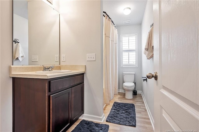 bathroom with toilet, vanity, and hardwood / wood-style floors