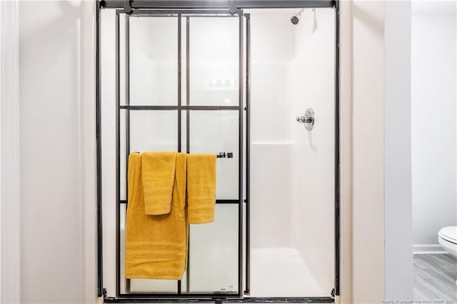 bathroom with walk in shower, hardwood / wood-style floors, and toilet