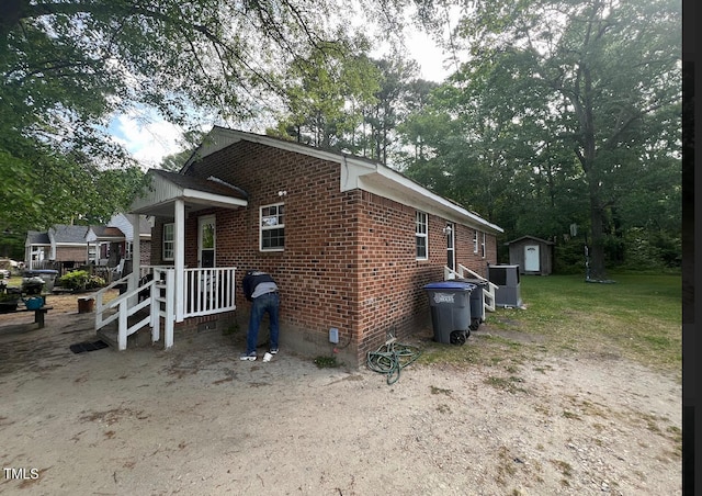 view of side of property with central air condition unit and a storage shed