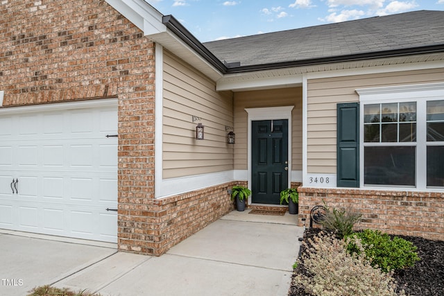 view of exterior entry with a garage, a shingled roof, and brick siding