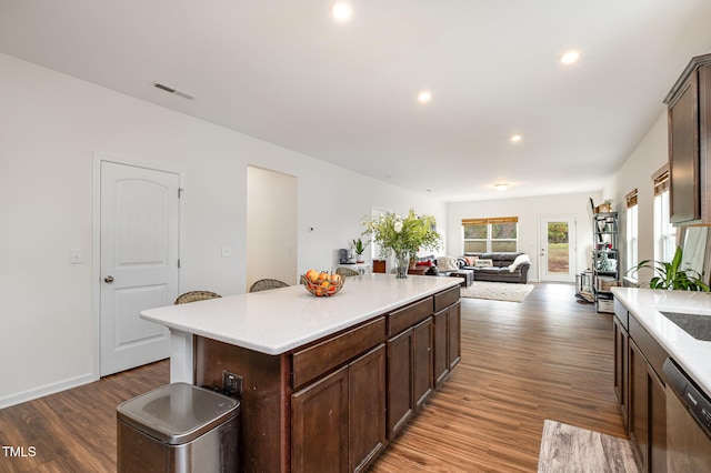 kitchen with light countertops, stainless steel dishwasher, wood finished floors, and visible vents