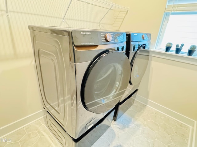 laundry area with washing machine and clothes dryer and light tile patterned flooring