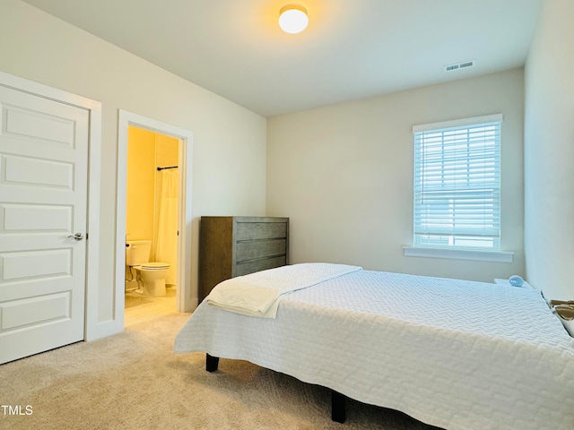 bedroom featuring connected bathroom and light carpet