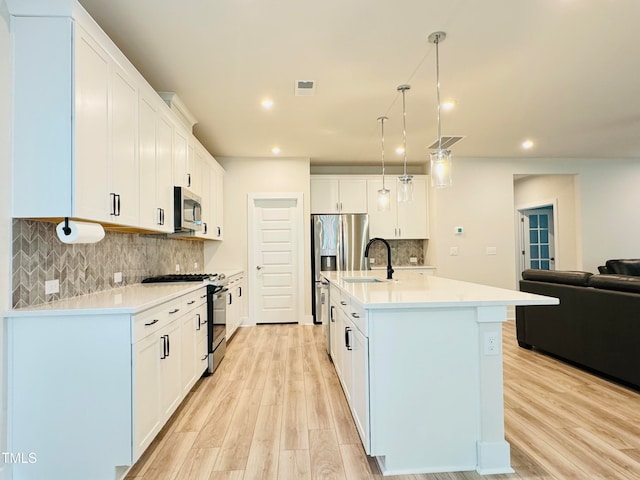 kitchen with white cabinetry, a kitchen island with sink, appliances with stainless steel finishes, and light hardwood / wood-style flooring